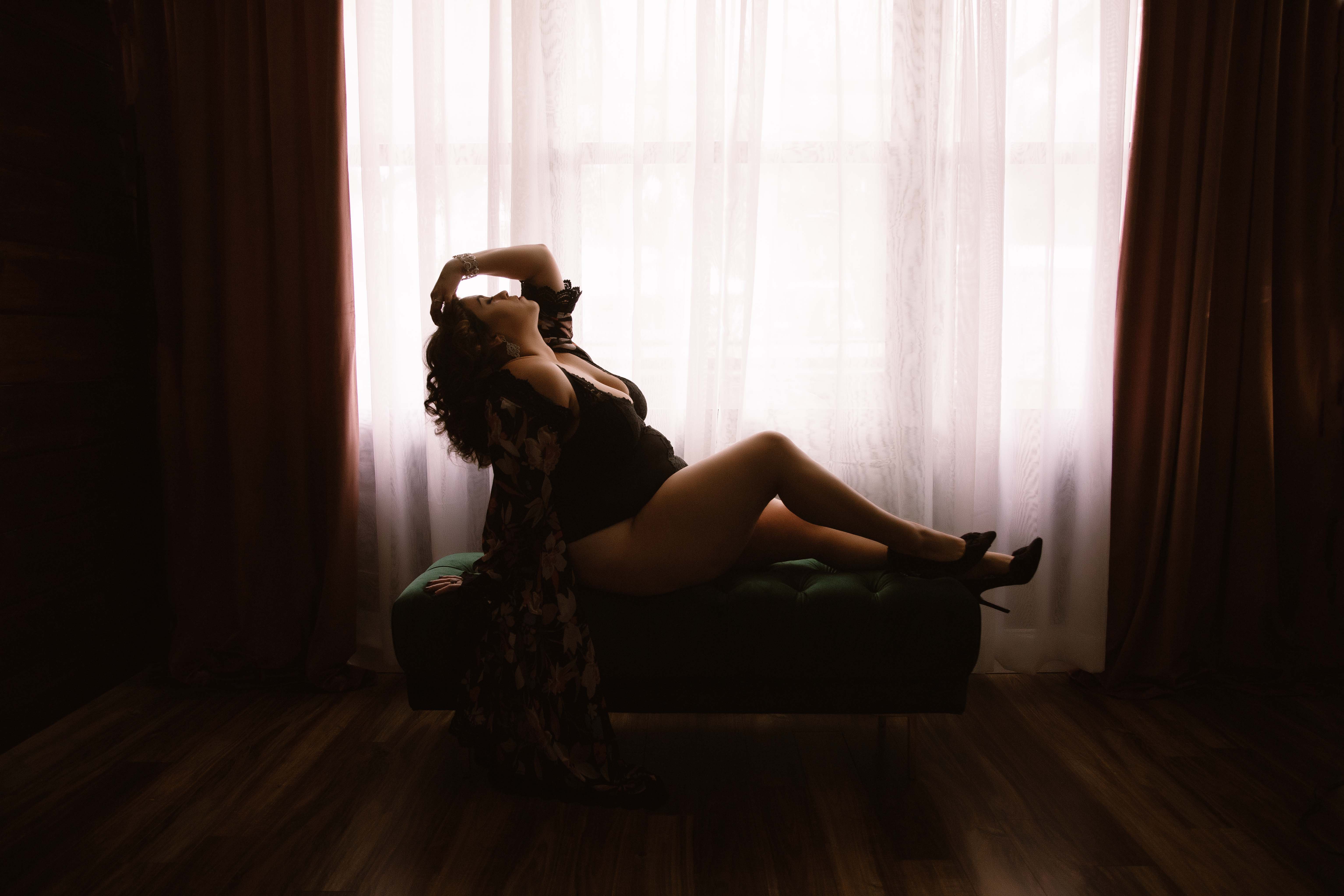 Silhouette of a woman posing in front of window for a boudoir photoshoot