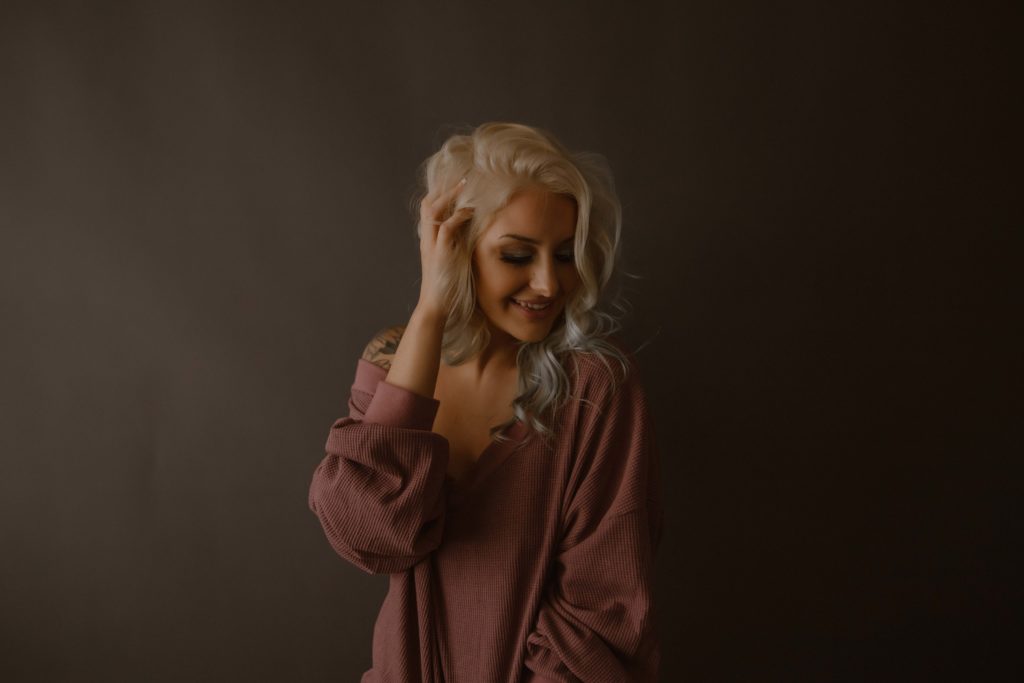 blonde wearing a mauve off the shoulder pullover sweater