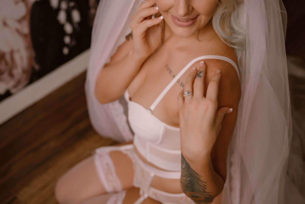 bride in lingerie, gazing at her engagement ring during a boudoir shoot