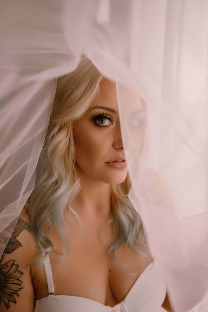 bride peeking out from behind a beautiful, gauzy veil 